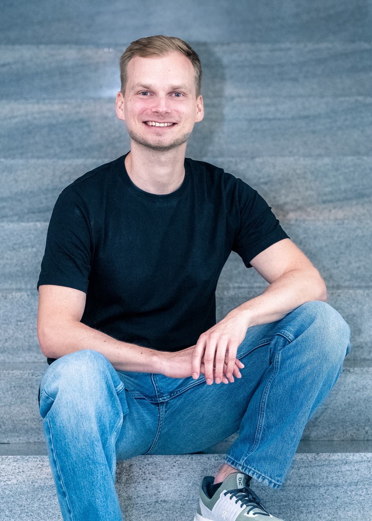 Fabian Herger sitzt auf einer Steintreppe und lächelt